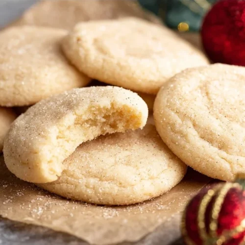 Batch of chewy sugar cookies on a baking tray, fresh out of the oven.